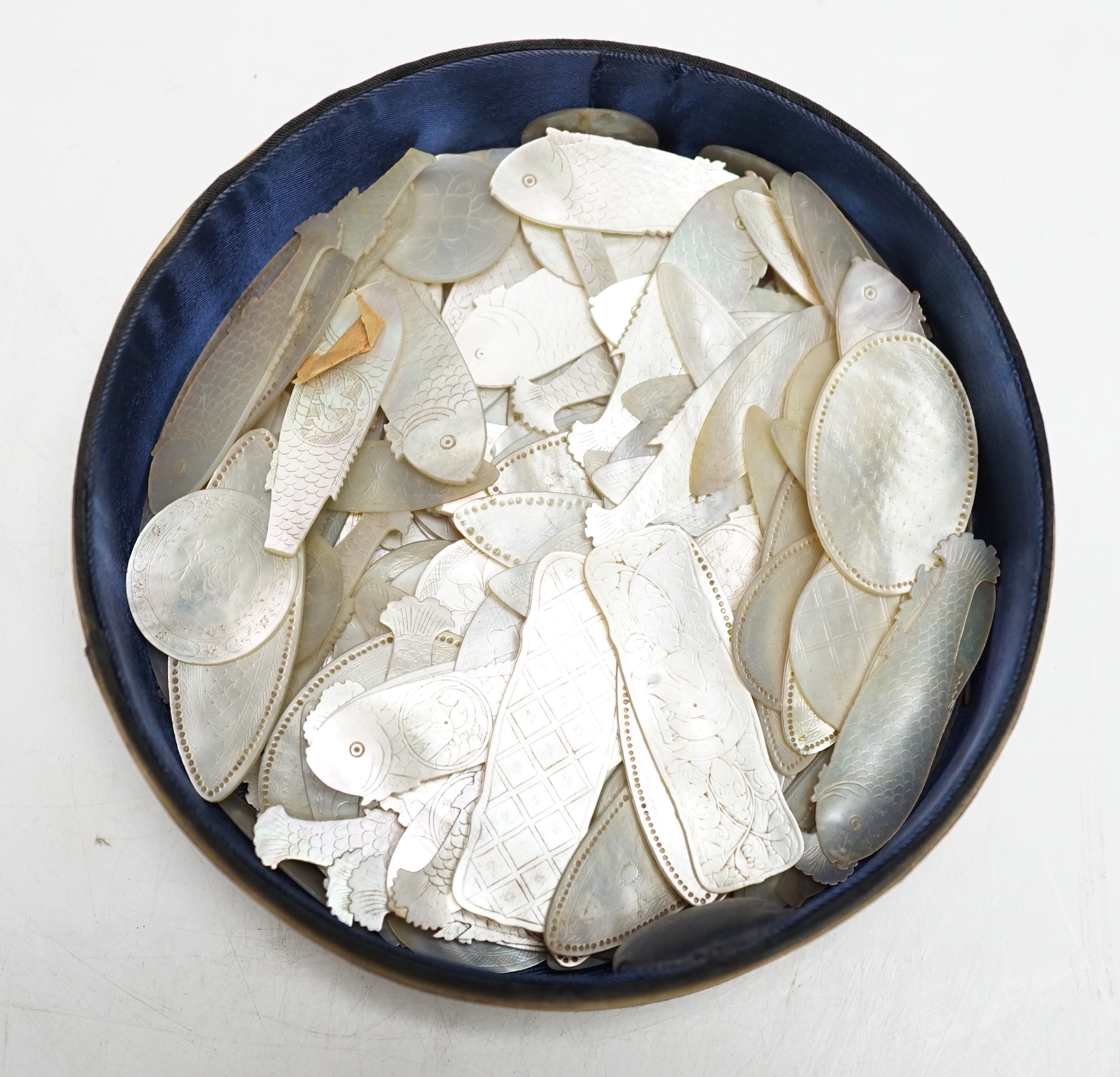 A collection of Chinese mother of pearl fish and other shaped counters